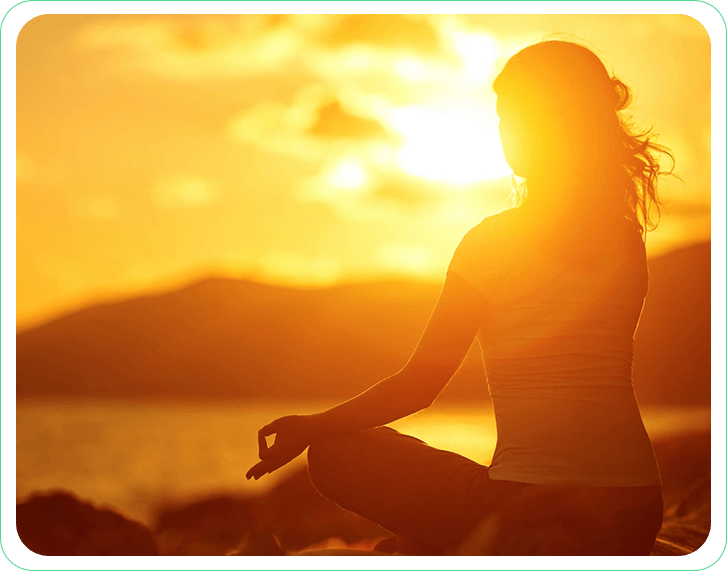 A woman sitting in the sun with her hands in yoga position.